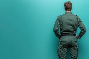 A border control officer stands with his hands on his hips, facing a solid-colored background. His uniform indicates authority and readiness, emphasizing the importance of his role in security. photo