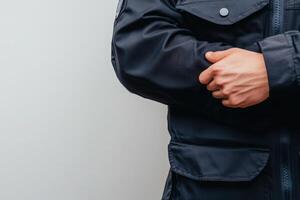 A border control officer stands with arms crossed, dressed in a dark uniform. The clean and solid background emphasizes the officers professionalism and readiness for duty. photo