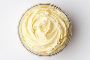 A smooth and creamy texture of heavy cream is displayed in a glass container, presenting a rich, buttery color. This ingredient is commonly used in various recipes and dishes. photo