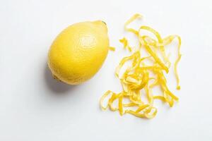 A vibrant whole lemon lies next to finely sliced lemon zest, showcasing the bright yellow color and fresh aroma. This arrangement highlights the fruits culinary potential and zests texture. photo