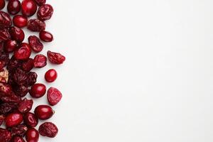 A variety of dried cranberries in rich red hues are arranged on a clean, solid white surface, highlighting their texture and color, perfect for healthy snacking or baking options. photo