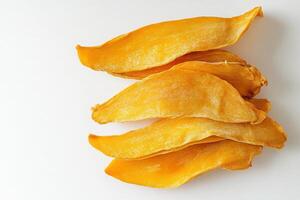 Dried mango slices are displayed on a clean solid white surface, showcasing their vibrant color and texture. These healthy snacks are perfect for enjoy anytime or adding to dishes. photo