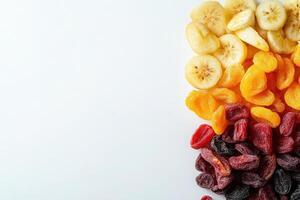 A vibrant assortment of dried fruits, including banana slices, apricots, and mixed berries, is neatly arranged on a solid white background, showcasing their appealing colors and textures. photo