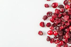 A collection of dried cranberries rests on a spotless white background, showcasing their deep red hue and varied shapes. Their vibrant appearance suggests a healthy snack option. photo
