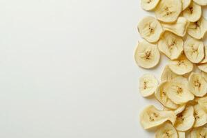 A variety of dried banana chips is neatly laid out on a pristine white surface, showcasing their natural texture and color, perfect for a nutritious snack or ingredient in recipes. photo