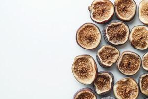 A collection of dried figs laid out on a pristine white surface highlights their rich texture and unique patterns, emphasizing their natural sweetness and health benefits. photo
