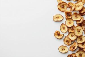 A collection of dried banana chips is artistically arranged on a clean white surface, highlighting their golden-brown color and texture. This image showcases a nutritious, crispy snack option. photo