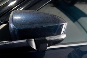 Mirror is painted a dark blue color and has drop of water rain around the edge. The mirror casing is curved and has a small. rectangular shape. The mirror itself is not visible in the image. photo