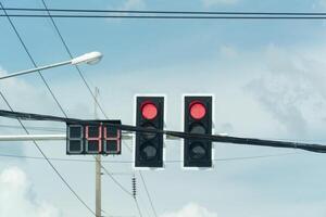 Traffic red lights control. Red lights indicate of vehicles must stop. Countdown timer to traffic light show no.44 suggesting of traffic light to change. Background of blue sky and electrical wires. photo