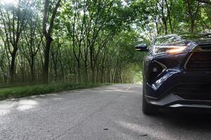 Car driving on a winding road surrounded by trees. Asphalt road is narrow and there are no other cars visible. Turn on headlights to indicate that it is dark or the driver is driving in a tree tunnel. photo