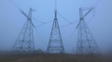 A tranquil morning unfolds as fog envelops towering power lines set against a serene landscape, showcasing the contrast between nature and infrastructure at dawn. video