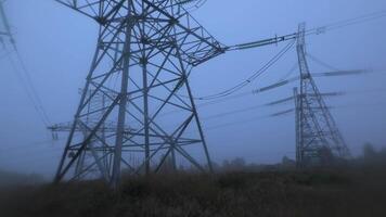 A serene early morning setting features towering power lines shrouded in thick fog, creating an atmospheric view of rural electricity infrastructure. video