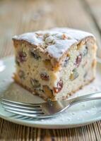 Close-up of a slice of fruitcake with powdered sugar, a fork halfway through photo