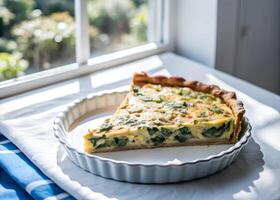 Side-shot of a slice of quiche being lifted from the whole, golden crust and creamy filling in focus, with natural light streaming through a window photo