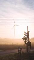 A wind turbine and railroad crossing sign in the morning video