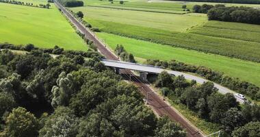 An aerial view of a train crossing a bridge over a green field video