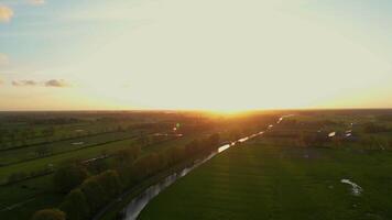 A sunset over a field with a river running through it video