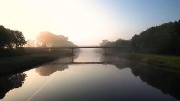 A bridge over a canal with fog and trees video