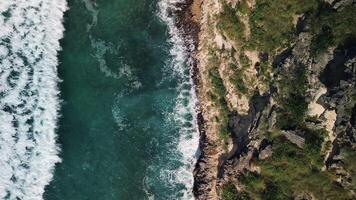 Aerial top view of wild tropical coast of Dominican Republic with rocky cliff and untouched nature.A light breeze rolls onto the shore with turquoise ocean waves.A luxurious landscape for relaxation video
