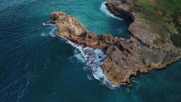 Aerial view of the wild tropical coast of the Dominican Republic with rocky cliff and untouched nature.A light breeze rolls onto shore with turquoise ocean waves.A luxurious landscape for relaxation video