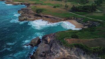 Aerial view of Enjoy the breathtaking bird's-eye view of the tropical sandy beach with rolling turquoise waves, the beauty of this unique corner. It offers stunning views of the golf courses. video