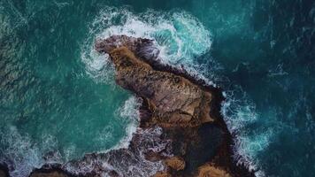 Aerial top view of coral rock washed by turquoise ocean waves in a storm. Powerful turquoise waves crashing against the rocks with thousands of sparkling splashes.Concept of tourism,travel,recreation. video
