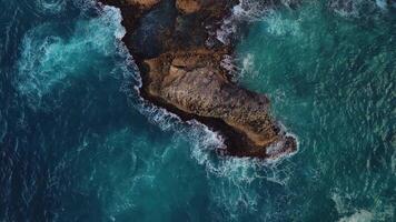 Aerial top view of coral rock washed by turquoise ocean waves in a storm. Powerful turquoise waves crashing against the rocks with thousands of sparkling splashes.Concept of tourism,travel,recreation. video