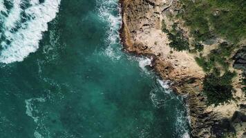 Aerial top view of wild tropical coast of Dominican Republic with rocky cliff and untouched nature.A light breeze rolls onto the shore with turquoise ocean waves.A luxurious landscape for relaxation video