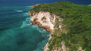 Atrial view of wild tropical coast of the Dominican Republic with rocky cliff and untouched nature.A light breeze rolls onto the shore with turquoise ocean waves.A luxurious landscape for relaxation video