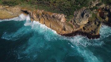 Aerial view of the wild tropical coast of the Dominican Republic with rocky cliff and untouched nature.A light breeze rolls onto shore with turquoise ocean waves.A luxurious landscape for relaxation video