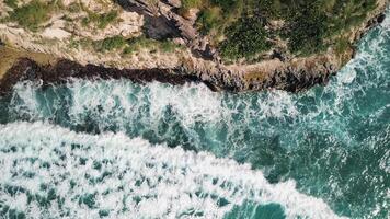 Aerial top view of wild tropical coast of Dominican Republic with rocky cliff and untouched nature.A light breeze rolls onto the shore with turquoise ocean waves.A luxurious landscape for relaxation video