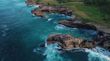 Aerial view of the wild tropical coast of the Dominican Republic with rocky cliff and untouched nature.A light breeze rolls onto shore with turquoise ocean waves.A luxurious landscape for relaxation video