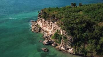 Atrial view of wild tropical coast of the Dominican Republic with rocky cliff and untouched nature.A light breeze rolls onto the shore with turquoise ocean waves.A luxurious landscape for relaxation video