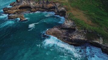 Aerial view of the wild tropical coast of the Dominican Republic with rocky cliff and untouched nature.A light breeze rolls onto shore with turquoise ocean waves.A luxurious landscape for relaxation video