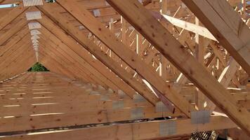 Wooden roof trusses in a construction site forming a symmetrical triangular pattern, with sunlight streaming through the gaps video