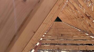 Symmetrical arrangement of wooden roof trusses on a construction site with a clear view through the beams to the sky video