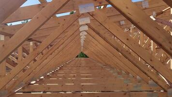 Close-up of wooden roof trusses forming a geometric pattern during the construction of a building under clear daylight video