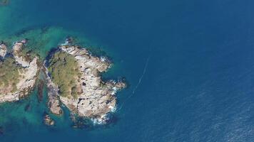 Rocky island washed by waves covered with coniferous trees in a sea bay video