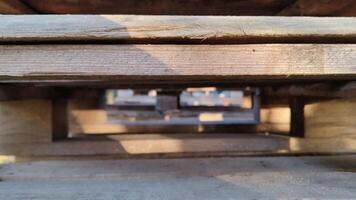 Close-up view through a stack of wooden pallets with sunlight casting shadows on the surface video