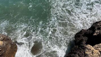 Waves crashing against rocky cliffs with turquoise sea foam evoke tranquility and adventure, ideal for summer travel and coastal exploration themes video