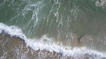 Aerial view of ocean waves gently crashing onto the sandy shore, evoking tranquility and summer vibes video