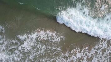 Aerial view of crashing ocean waves creating white frothy patterns, ideal for summer and beach vacations video