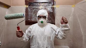 A person in protective gear holds a paint roller, preparing for home renovation tasks video