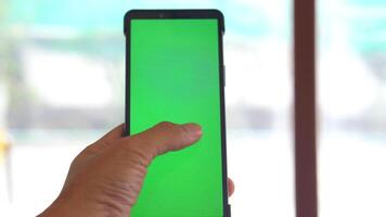 A person's hand is holding a smartphone with a green screen. The person's fingers are touching the screen according to the movement of the application. video