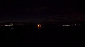 Two trains crossing in dark night over bridge and river as tranquil commuting or commuter travelling home or to work early morning late evening video