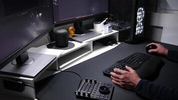 European man film editing in home office with ergonomic keyboard and ergonomic mouse and special device for motion editing as professional visual editor and motion graphics designer with two monitors video