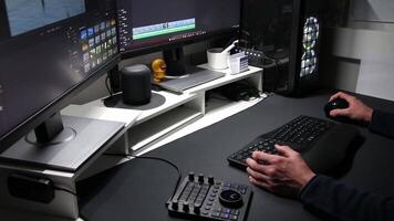 European man film editing in home office with ergonomic keyboard and ergonomic mouse and special device for motion editing as professional visual editor and motion graphics designer with two monitors video