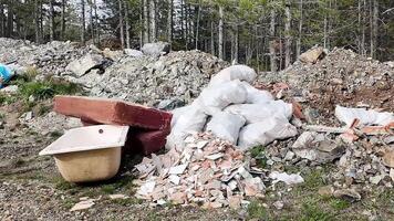 Dump site with construction debris and garbage bags in a forested area pollution, environment video