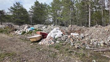 Piles of construction waste and discarded items in a forest, highlighting environmental pollution concerns video