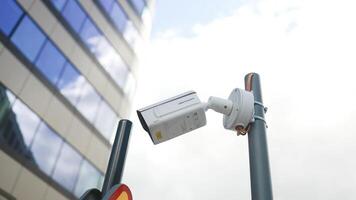 Security camera at the corner of building moving and scanning street area. Close-up of a surveillance camera mounted on the facade of a building business centre. video